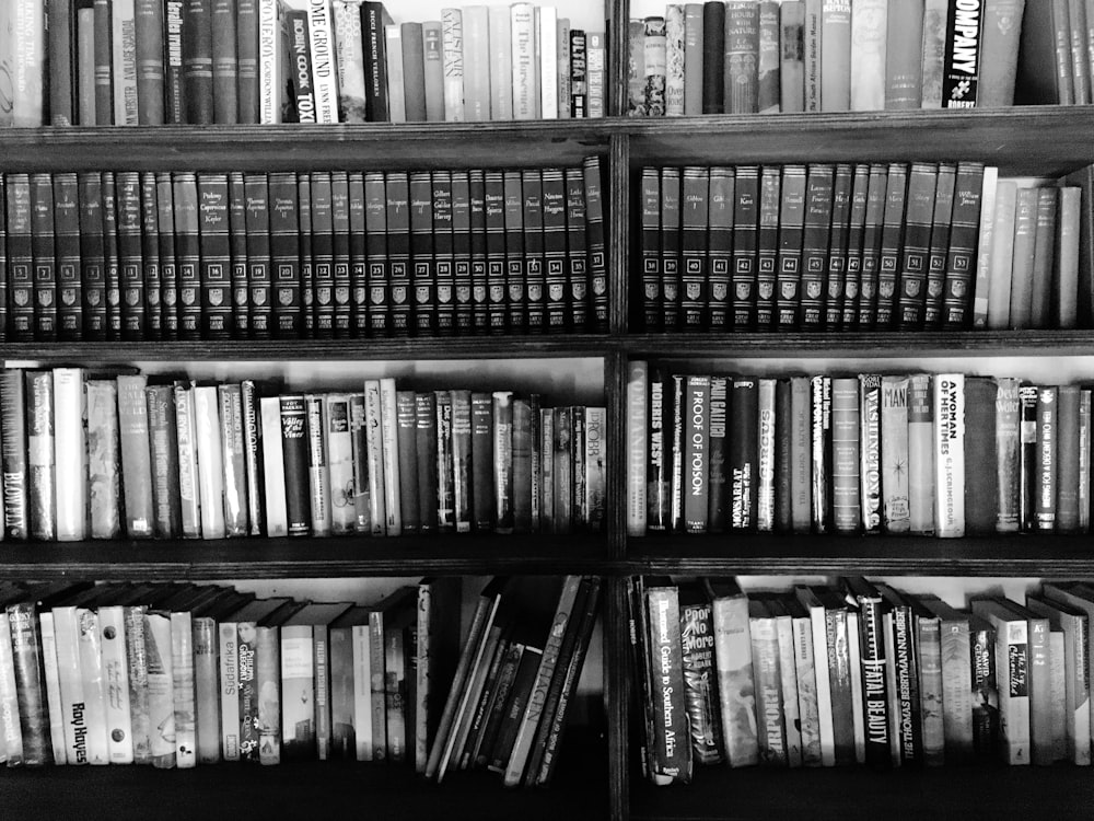 grayscale photo of books on shelves