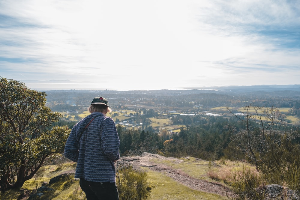 man in green and black plaid dress shirt standing on hill during daytime