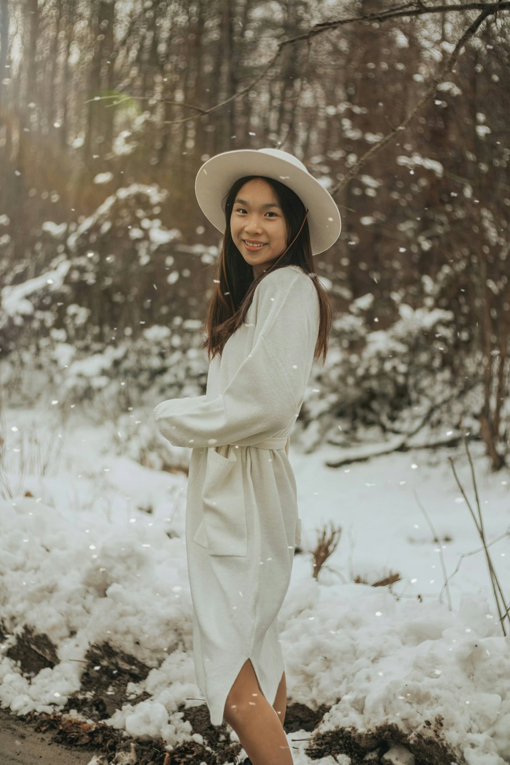 woman in white long sleeve dress and white hat standing on snow covered ground during daytime