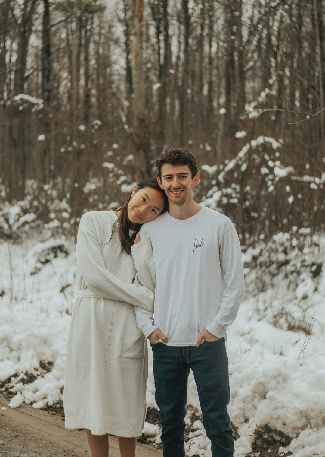 man in white sweater standing on snow covered ground during daytime