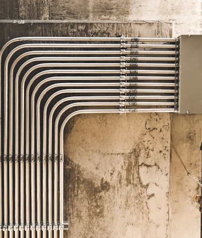 grey metal pipe on brown concrete wall