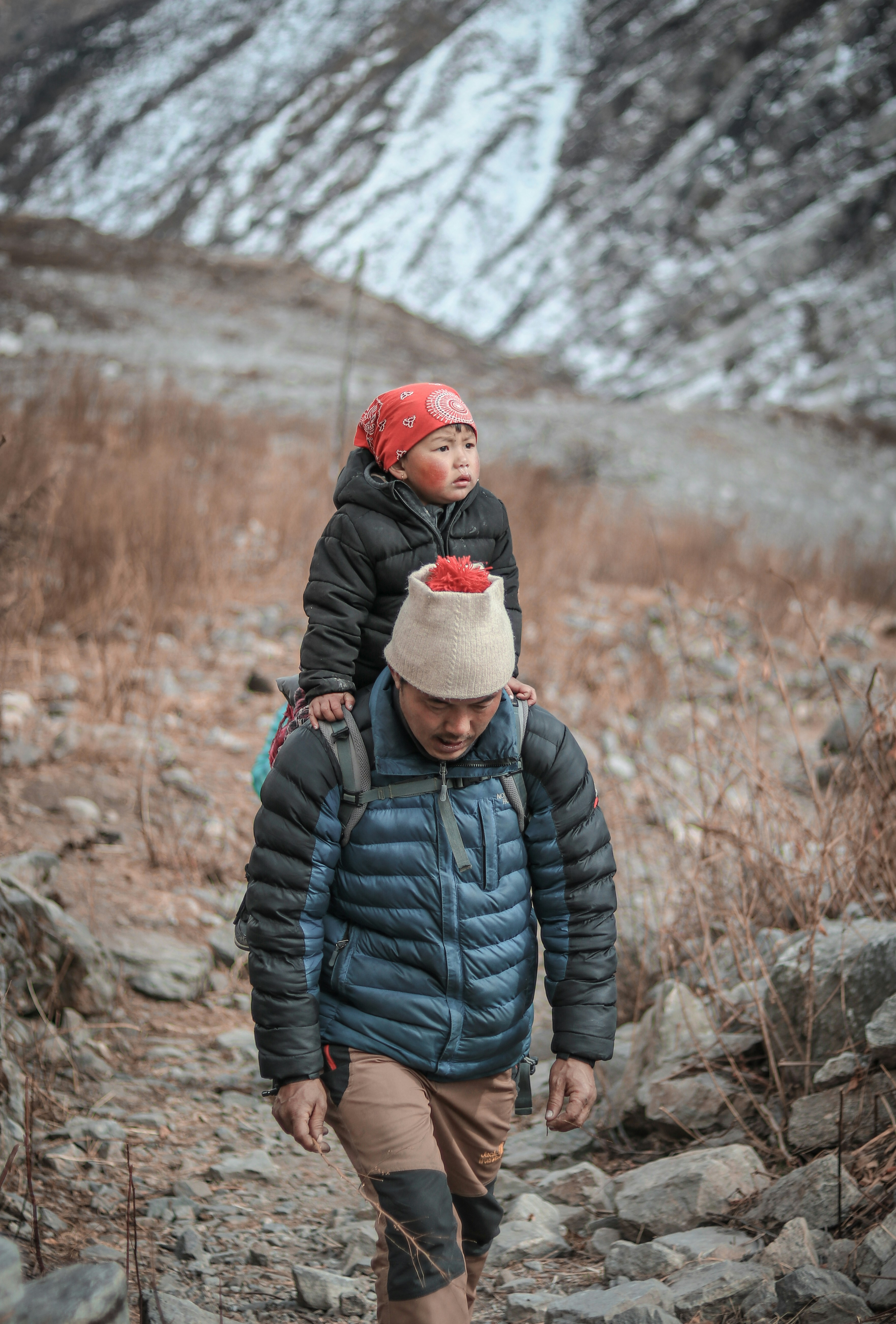 woman in black bubble jacket and red knit cap standing on rocky ground during daytime
