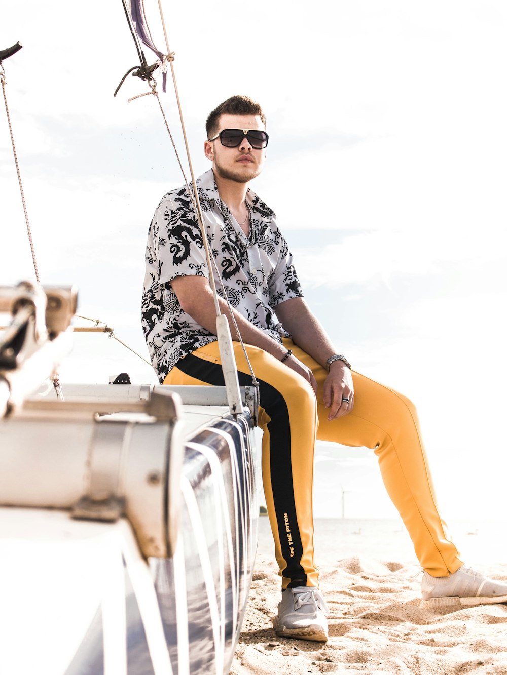 man in black and white floral shirt and orange pants wearing black sunglasses