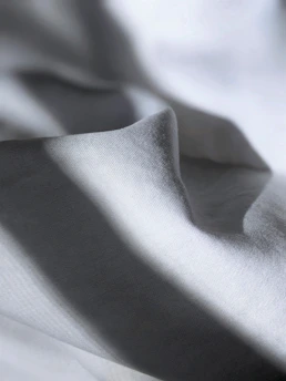 Soft folds of high-quality fabric in neutral tones, highlighted by gentle natural light.