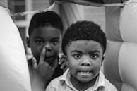 Children making silly faces in front of a colorful, playful backdrop inside the photo booth.
