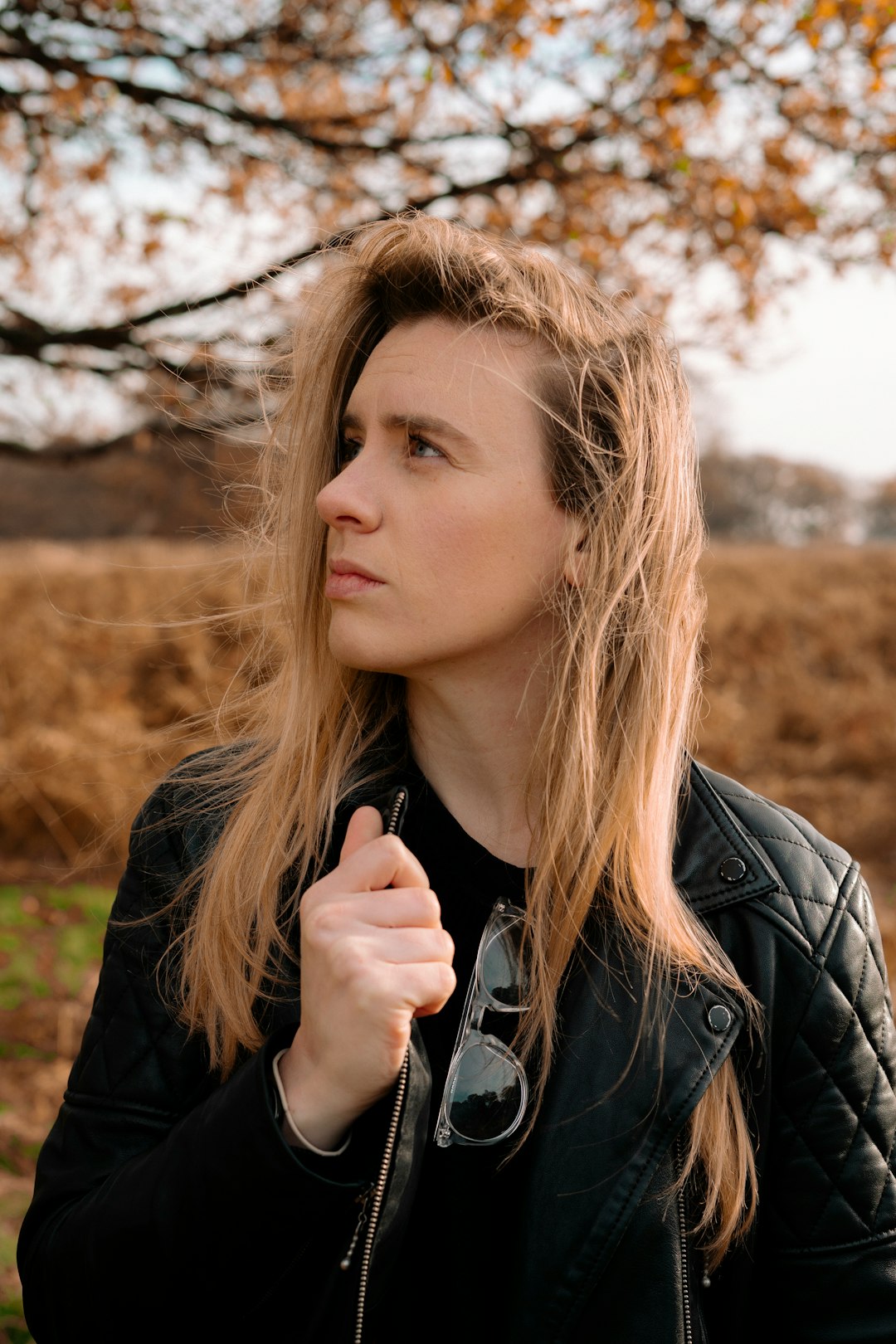 woman in black leather jacket holding her hair