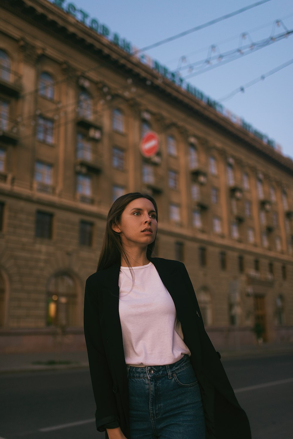 woman in black blazer standing near brown building during daytime