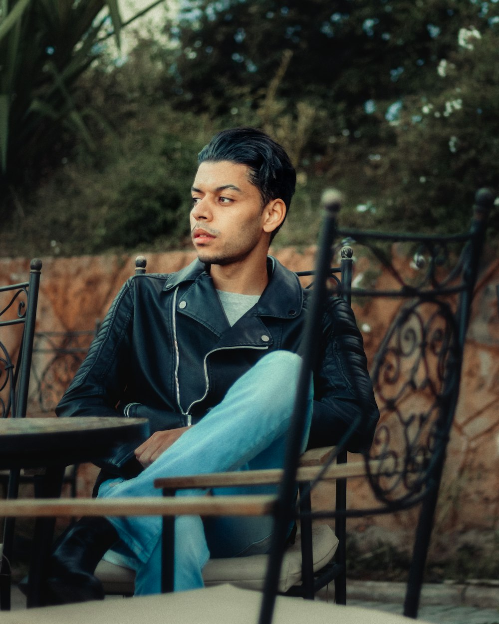 man in black jacket sitting on brown wooden bench