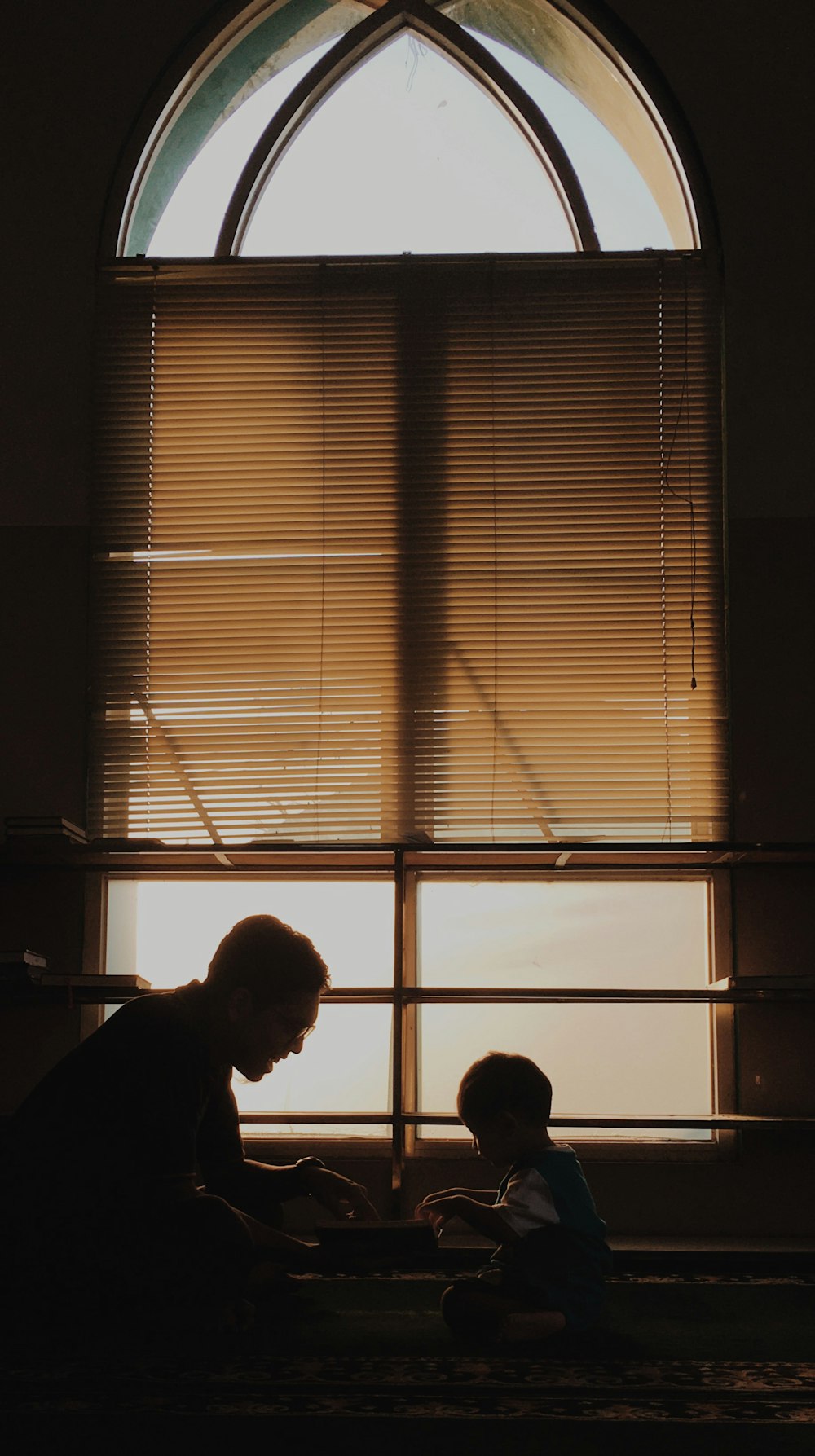 silhouette of man standing near window blinds