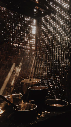 Sunlight filtering through rustic wooden beams onto a collection of artisan pottery.