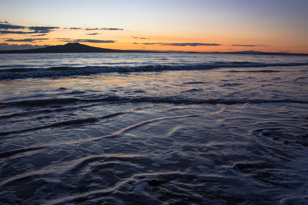 ocean waves crashing on shore during sunset