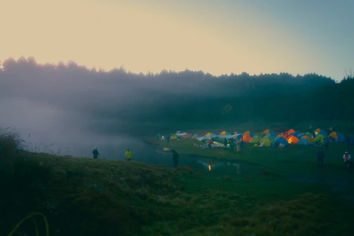 A serene morning scene with festival-goers lounging on soft grass, wrapped in colorful shawls.