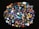 A collection of colorful, polished gemstones scattered on a dark surface. The stones have a variety of shapes, including triangles and ovals, with complex patterns and vibrant hues like blues, reds, yellows, and greens.