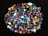 A collection of colorful, polished gemstones scattered on a dark surface. The stones have a variety of shapes, including triangles and ovals, with complex patterns and vibrant hues like blues, reds, yellows, and greens.