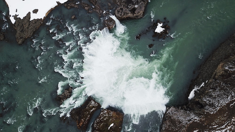 aerial view of ocean waves hitting rocks during daytime