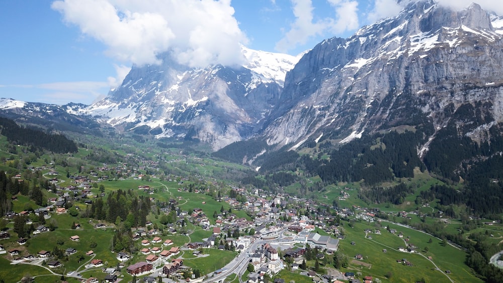 houses on green grass field near mountains under white clouds and blue sky during daytime