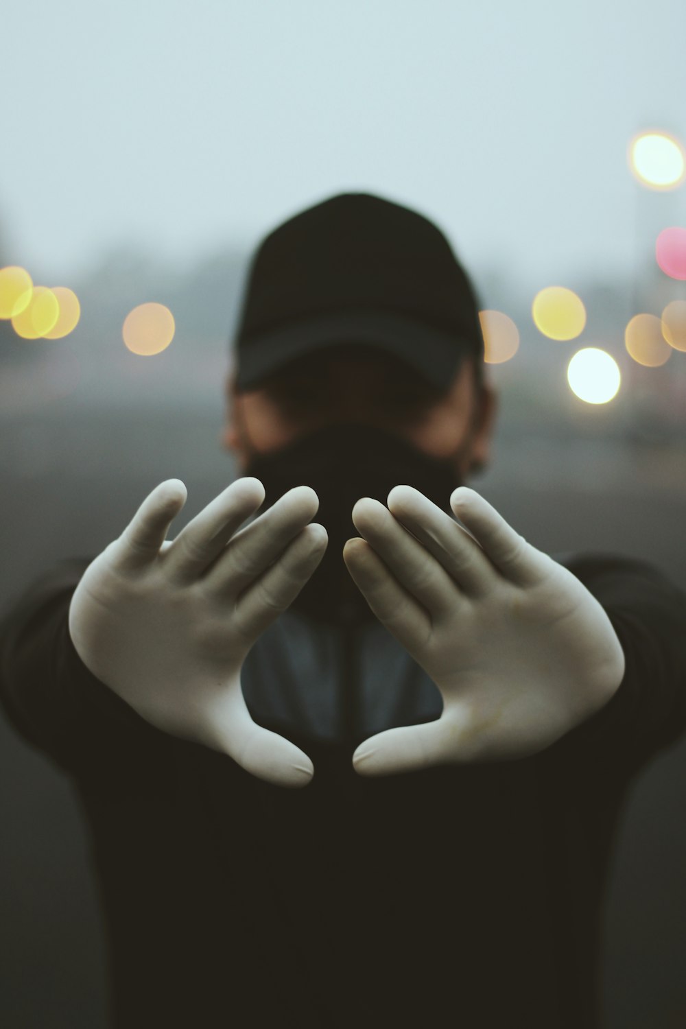 person wearing black knit cap covering face with hands