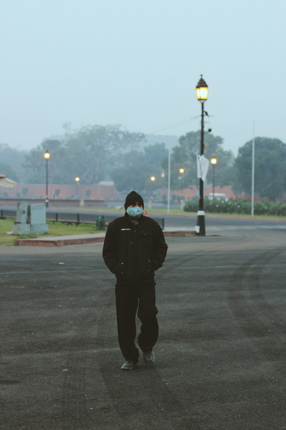 man in black jacket standing on gray asphalt road during daytime