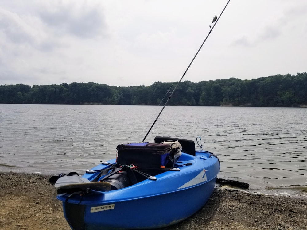 blue and white kayak on shore during daytime