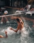 man in swimming pool playing volleyball during daytime