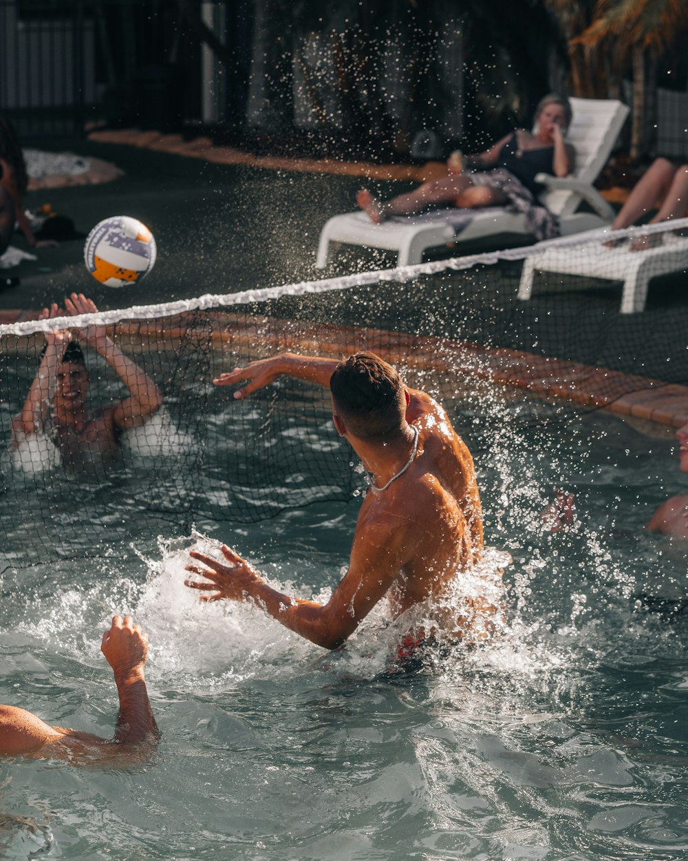 Mann im Schwimmbad, der tagsüber Volleyball spielt