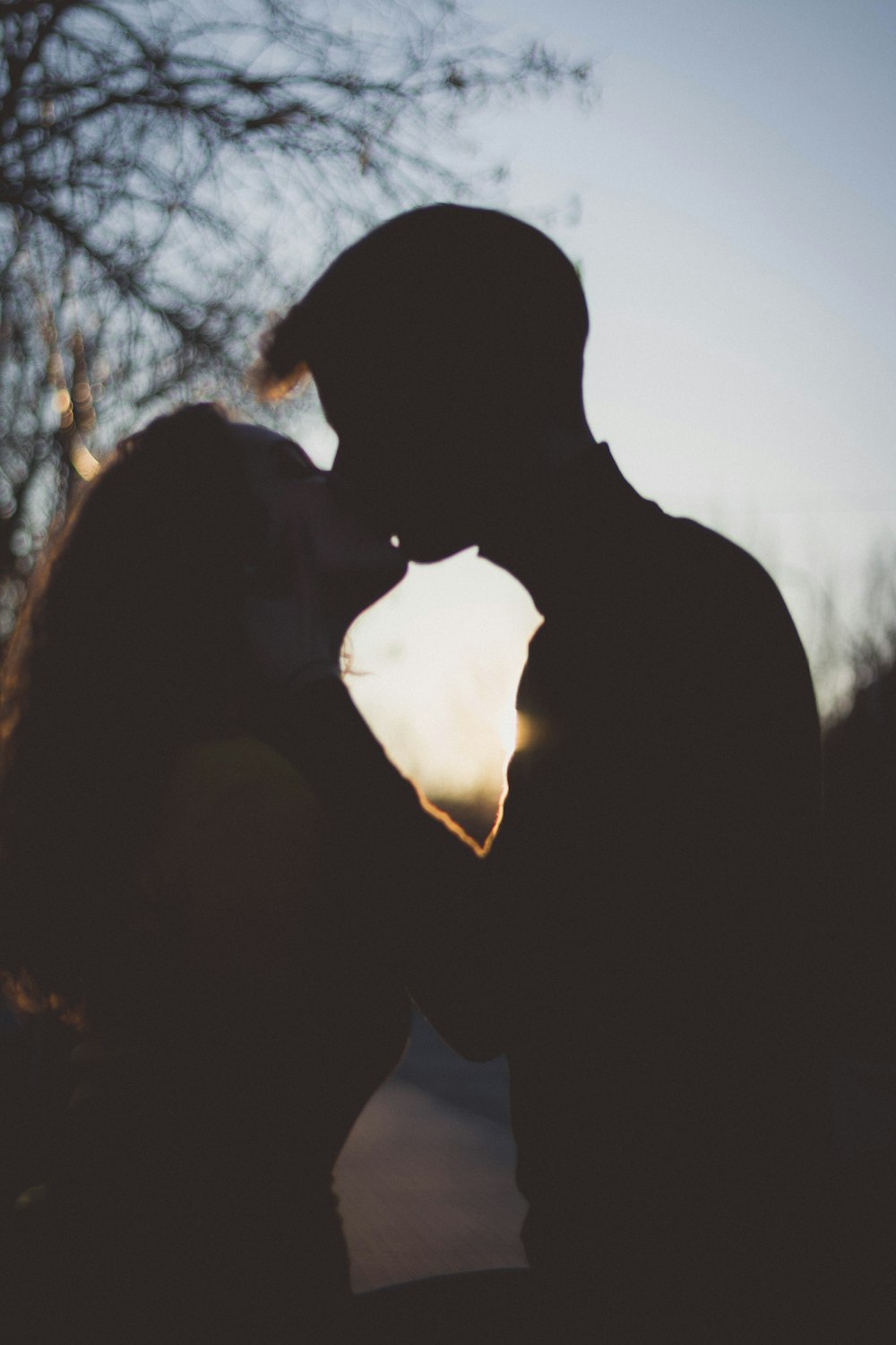 silhouette of man and woman kissing during sunset