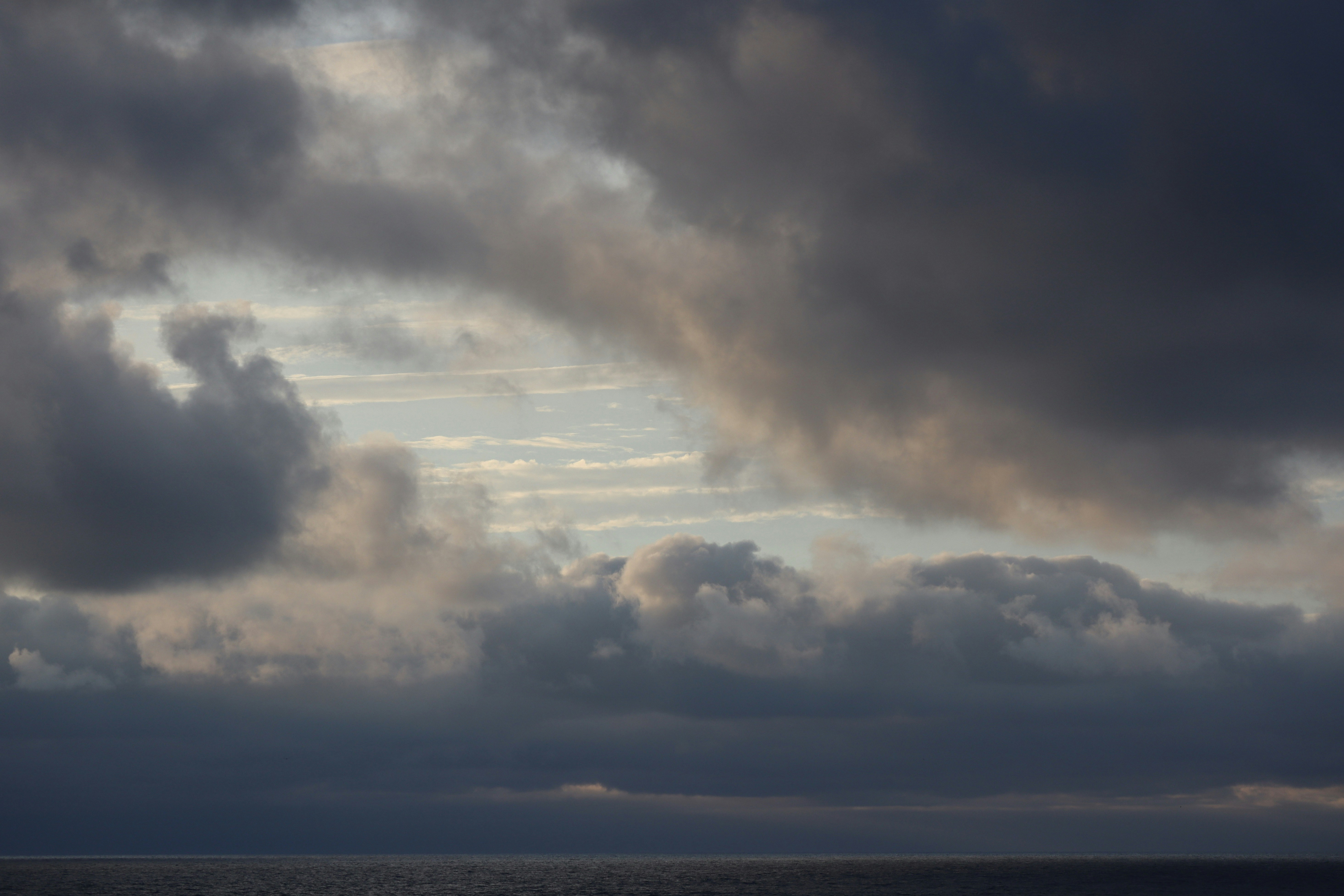Dark night sky with dramatic clouds, deep black atmosphere, faint horizon light, powerful ominous mood