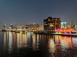 Night cityscape with vibrant lights reflecting on a river, full of life.