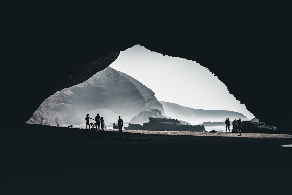 silhouette of people standing on grass field near mountain during daytime