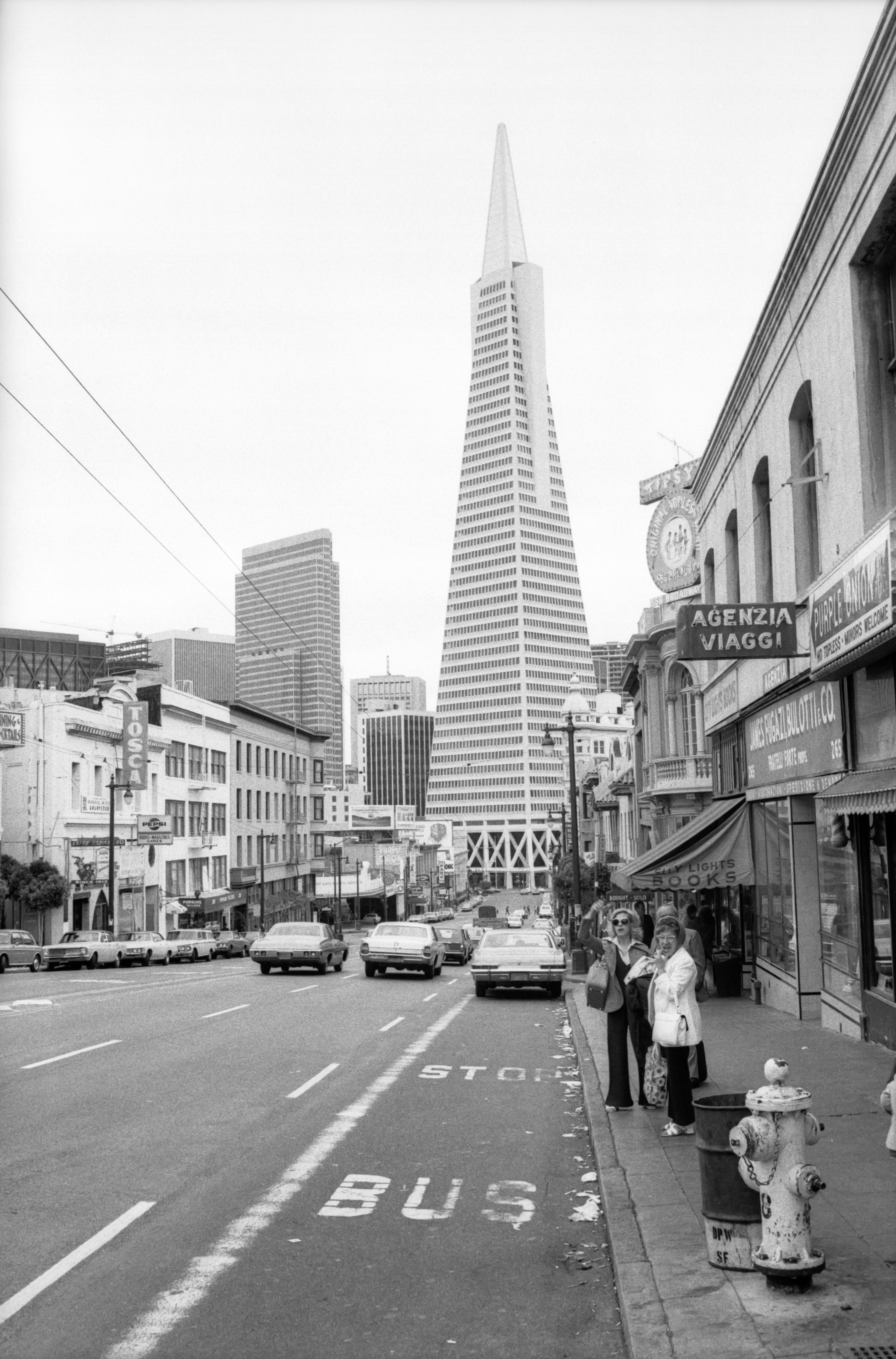 grayscale photo of man and woman walking on pedestrian lane