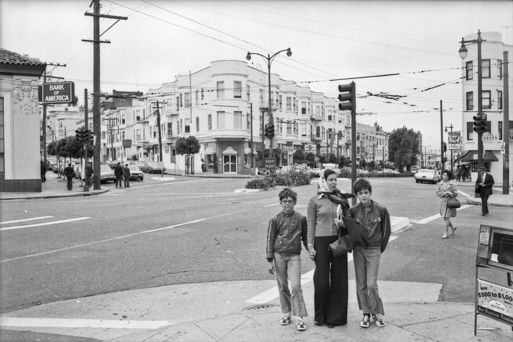 man and woman walking on sidewalk near traffic light in grayscale photography