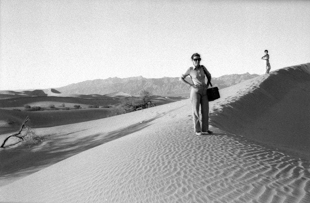 woman in black jacket and gray pants standing on gray sand during daytime