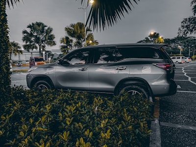 A family loading luggage into a spacious SUV parked near a palm tree-lined road.