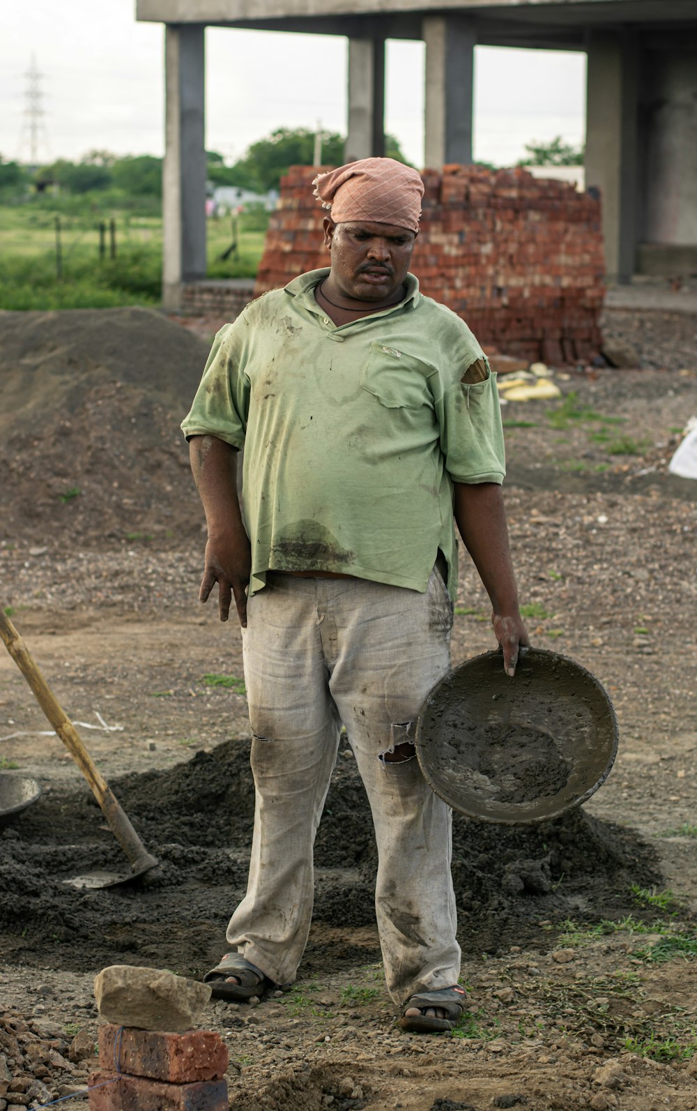 man in green polo shirt and brown pants standing near round brown wooden table during daytime