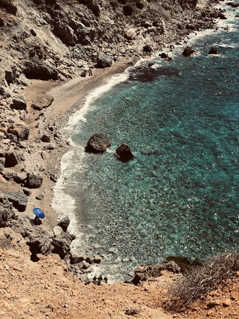 Formazione rocciosa marrone accanto allo specchio d'acqua durante il giorno