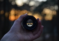 Close-up of a camera lens reflecting a rustic mountain ranch at golden hour.
