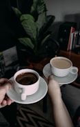 person holding white ceramic teacup with saucer