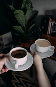 person holding white ceramic teacup with saucer