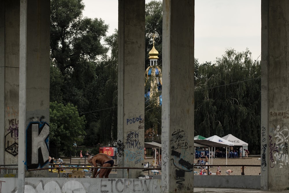 personnes debout près d’un pilier en béton gris pendant la journée