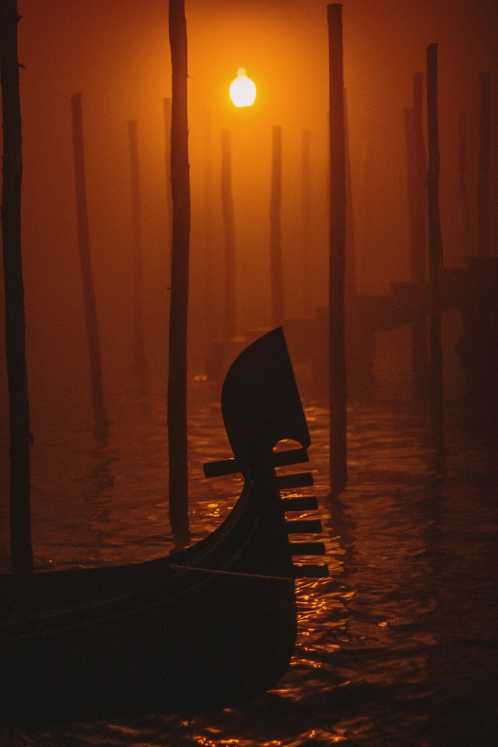 black boat on body of water during sunset