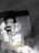 A bottle of Chanel No. 5 Eau de Parfum is placed in the foreground, exhibiting its classic and elegant glass design. Behind it, a Prada Milano bag can be seen, adding a touch of luxury. The background is softly blurred, giving prominence to the perfume bottle.