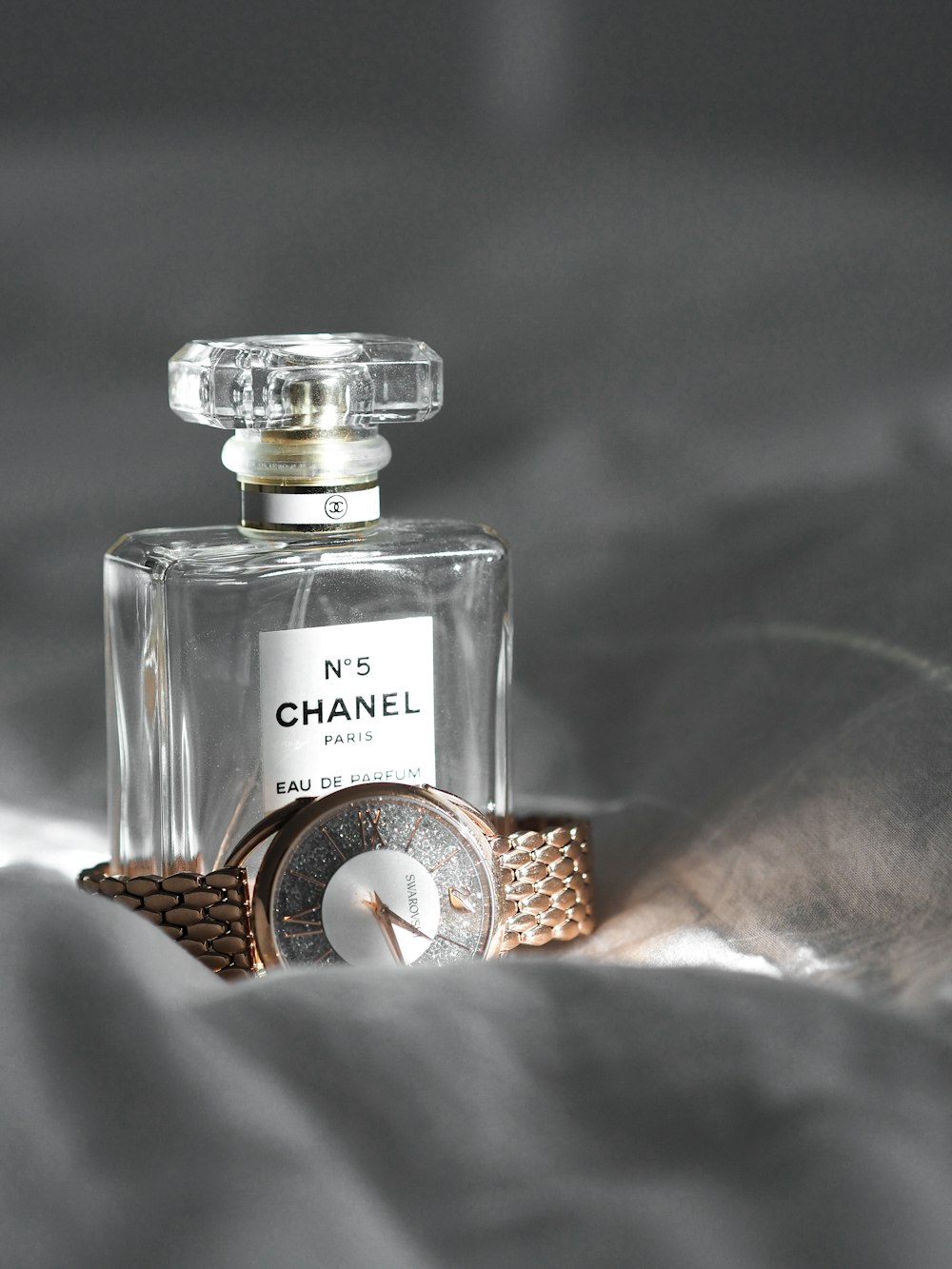 a bottle of chanel perfume sitting on top of a bed
