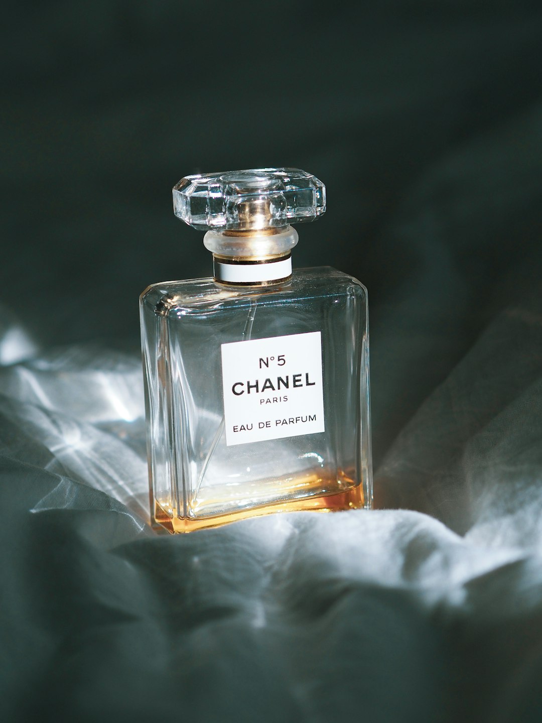 clear glass perfume bottle on white textile