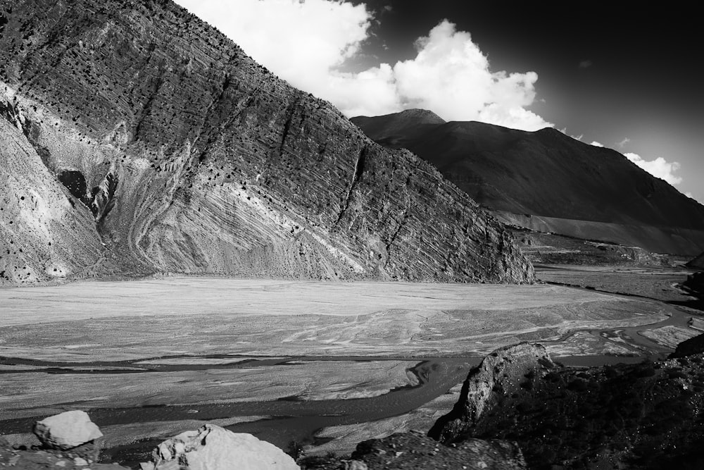 grayscale photo of mountain range under cloudy sky