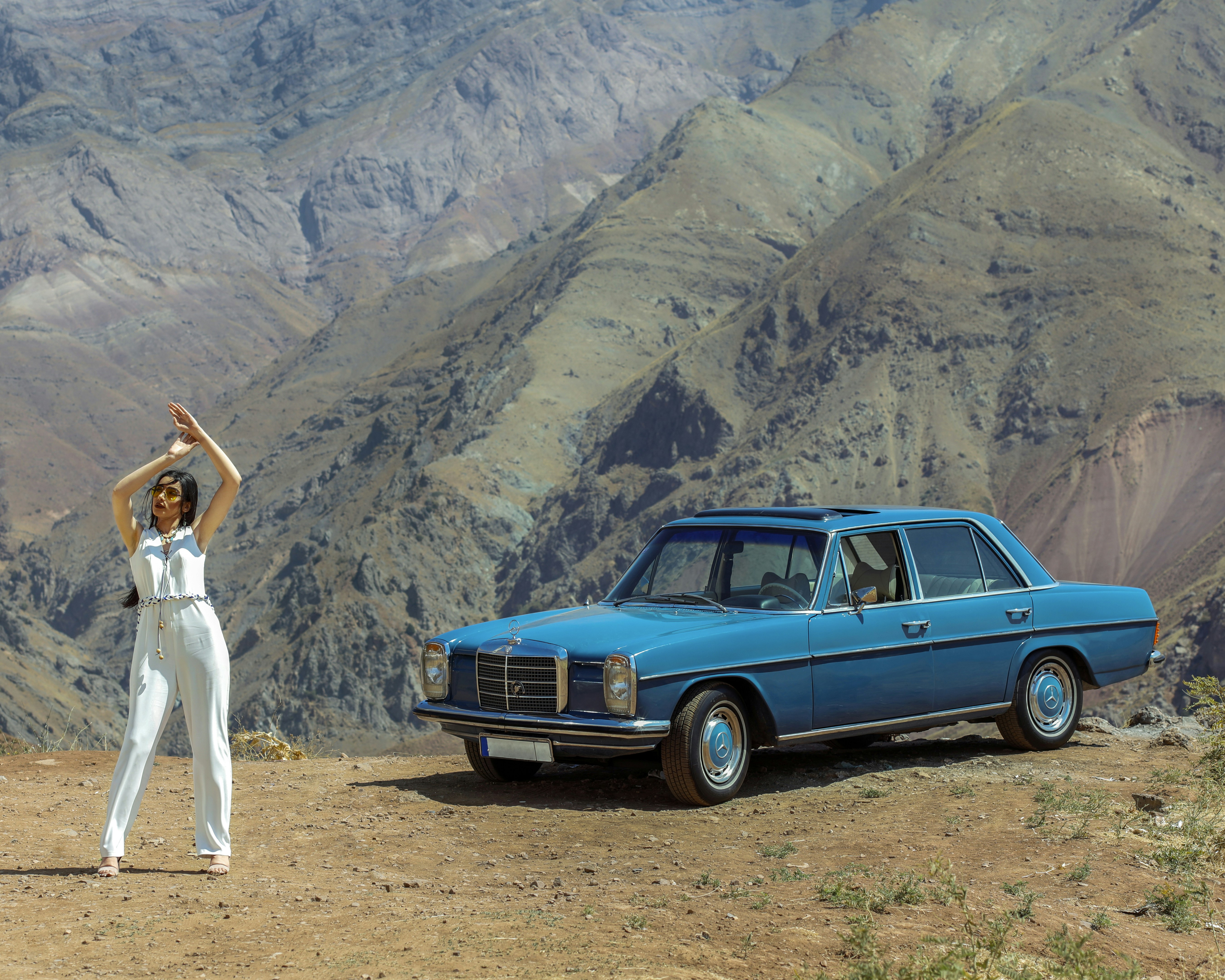woman in white dress standing beside blue car during daytime