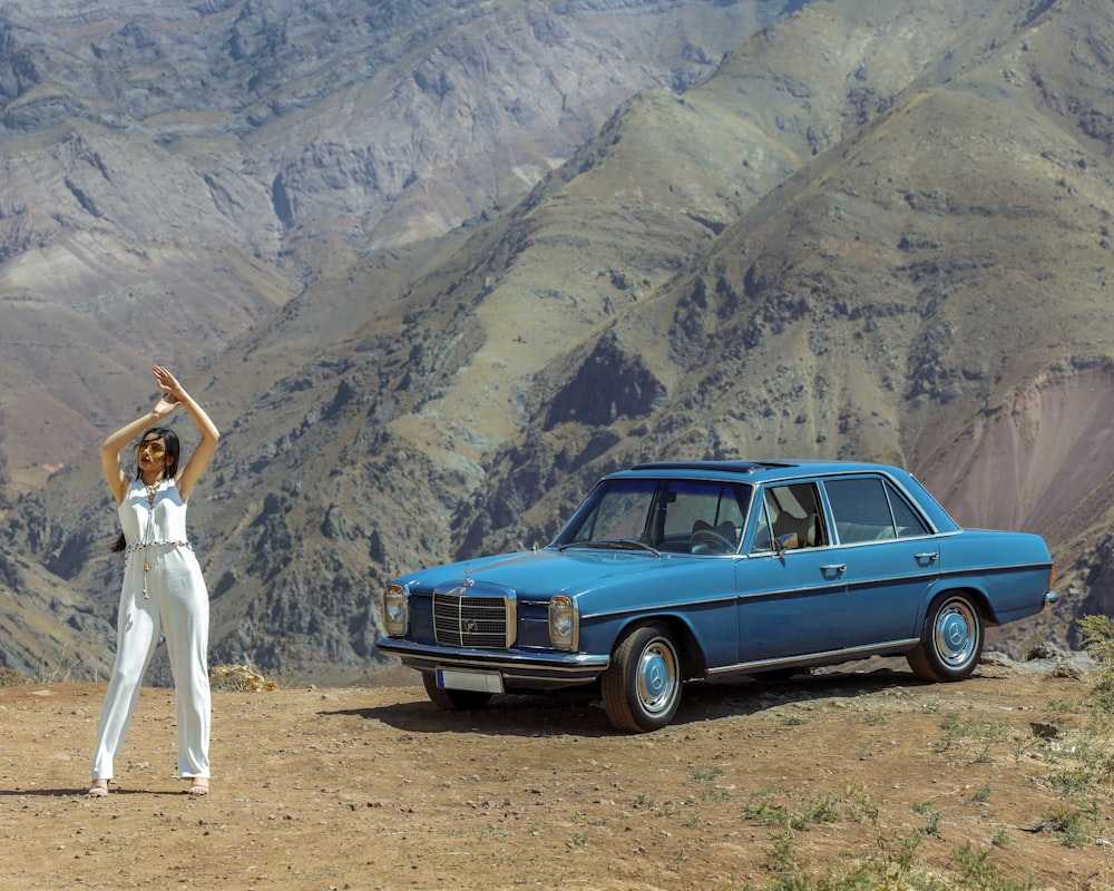 woman in white dress standing beside blue car during daytime