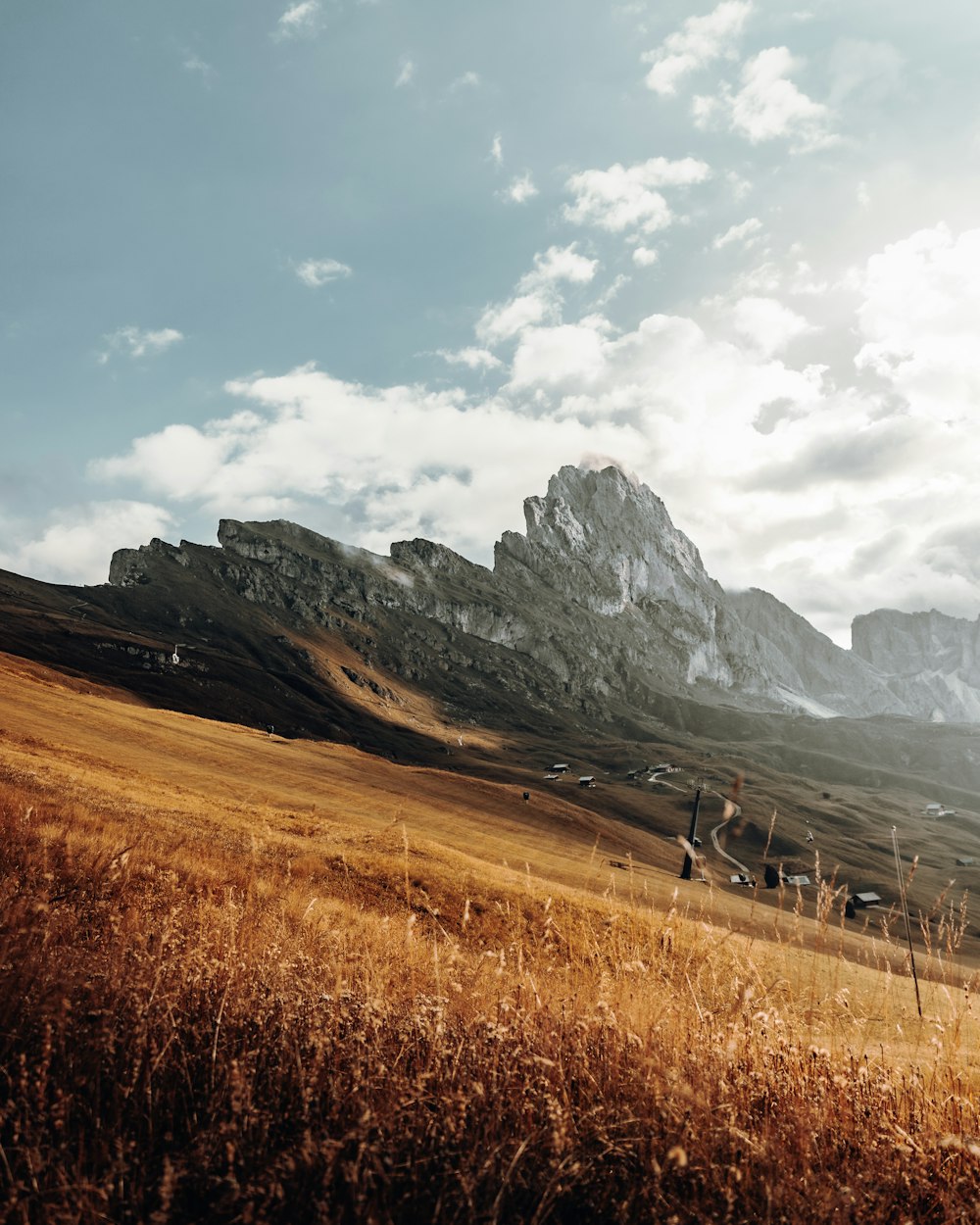 brown grass field near mountains under white clouds during daytime