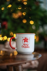 white and red ceramic mug on brown wooden table
