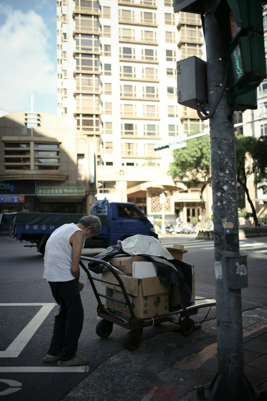 man in white t-shirt and black pants sitting on black metal cart on road during