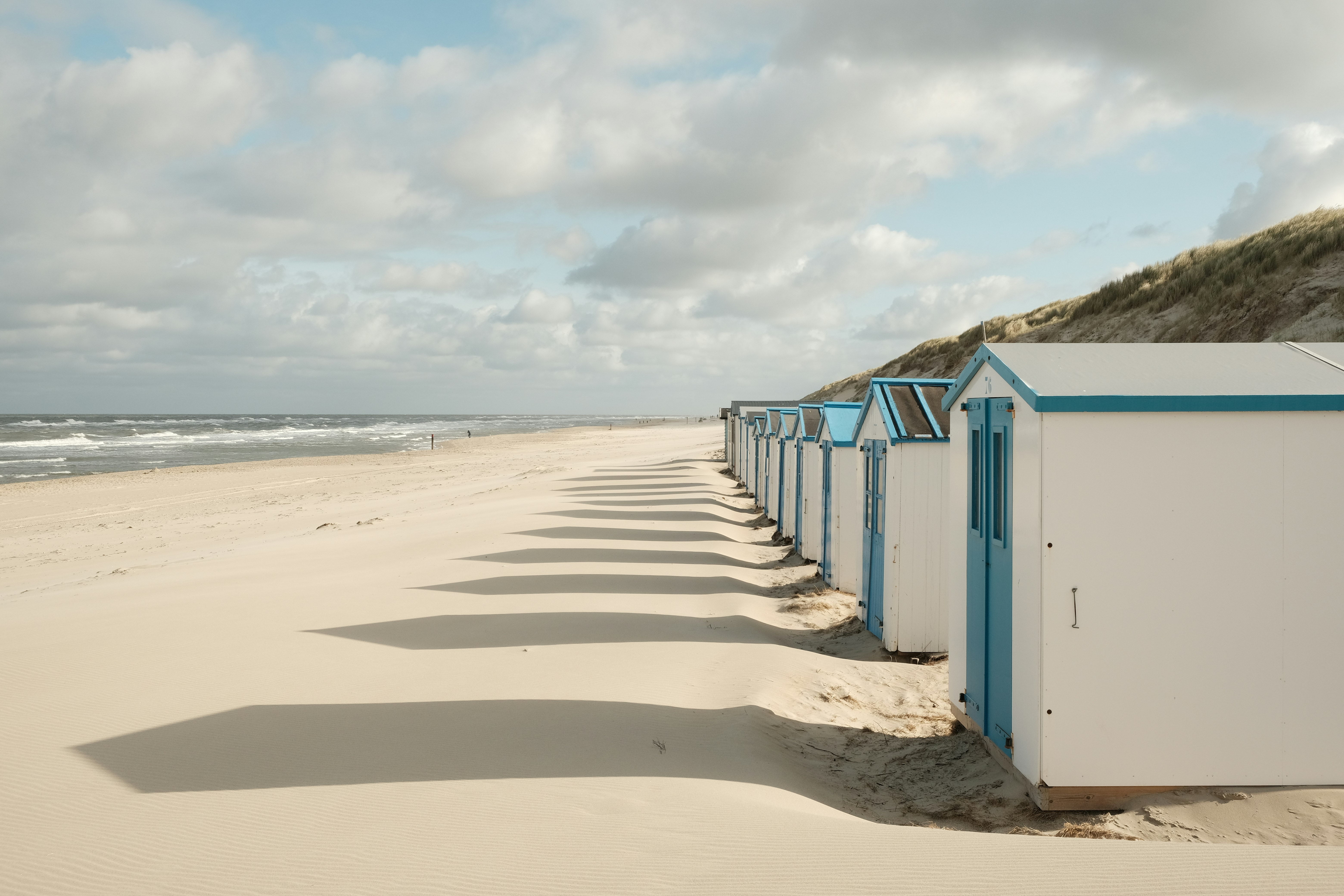 beach houses on the beach of Texel, NL, during a cloudy day with dramatic shadows.